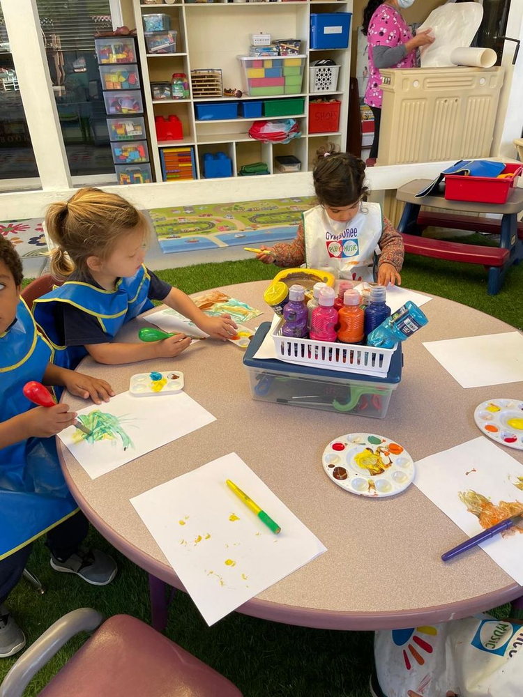 Children painting at the art table with brushes and paint palettes