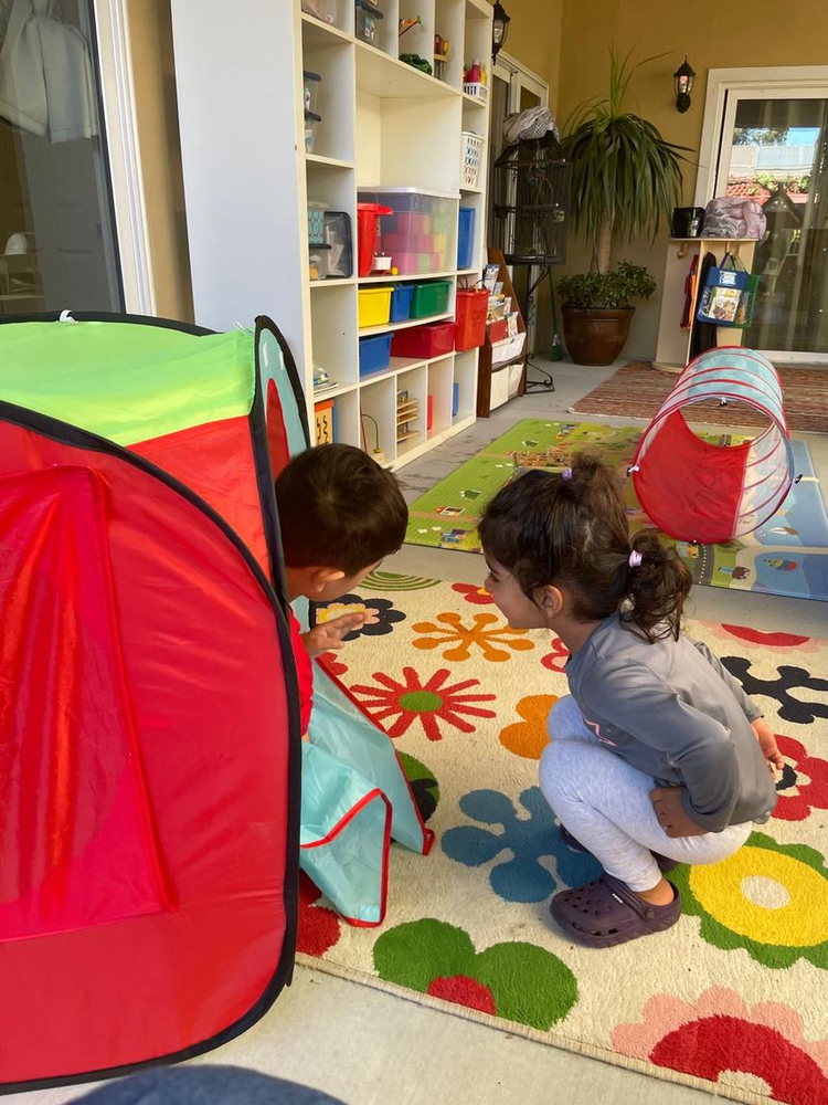 Children playing on the alphabet rug beside the reading tent