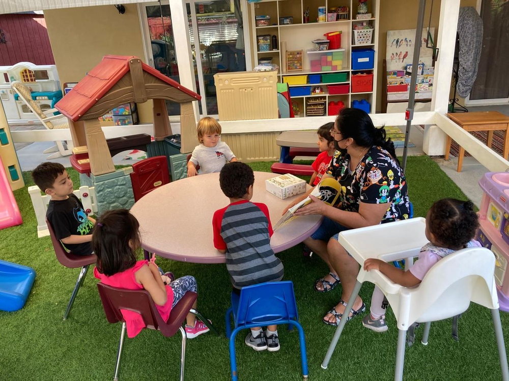 Eliza reading a story to a group of children seated around the table
